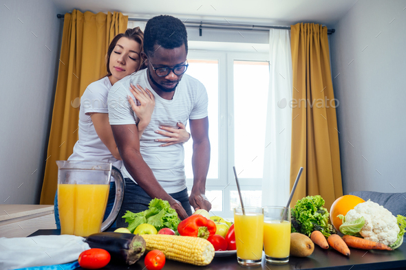 african american man with asian woman making smoothie at home, useing eco tubes from metall