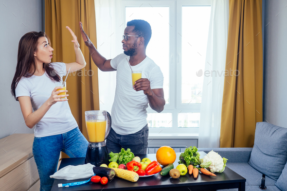 african american man with asian woman making smoothie at home