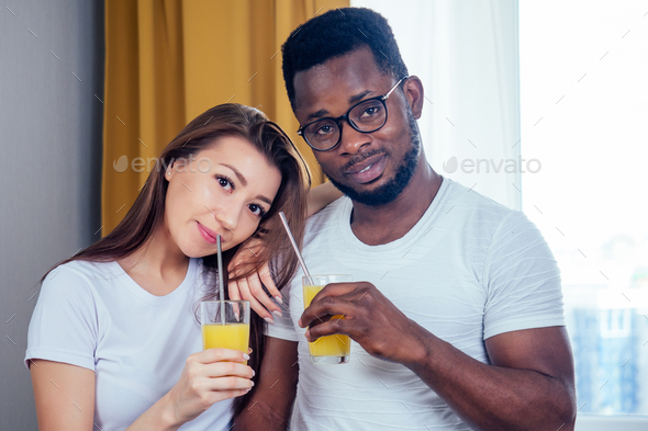 african american man with asian woman making smoothie at home, useing eco tubes from metall