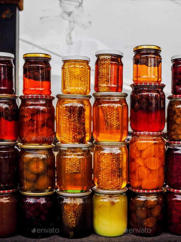 stacks of jars with honey and pickled fruits on farmers market at armenia