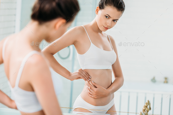 young woman in underwear looking at mirror in bathroom Stock Photo by  LightFieldStudios