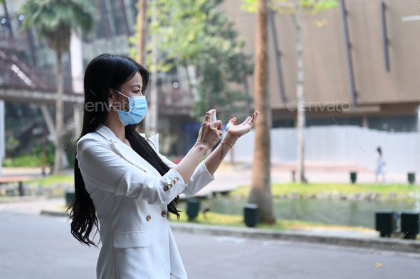 Businesswoman in protective mask applying spray disinfection alcohol on hand prevent the virus.