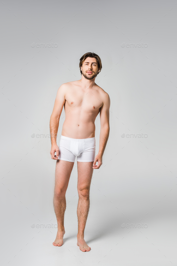 young man in white underwear posing on grey backdrop Stock Photo