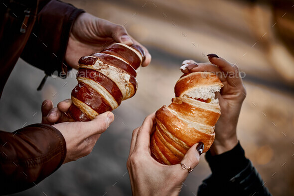 Close-up of couple's hands with croissant - Stock Photo - Images
