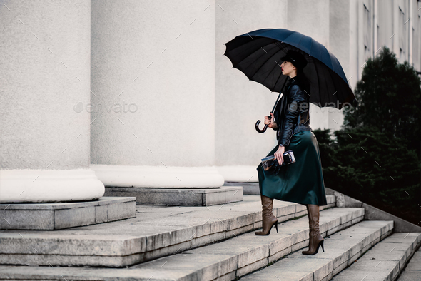 Young woman under an umbrella walking the stair - Stock Photo - Images