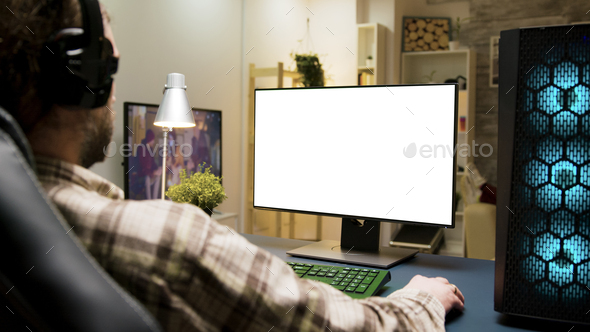 Man with headphones playing games on computer with green screen