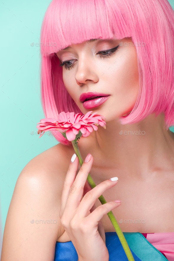 beautiful young woman with pink bob cut holding flower isolated on turquoise
