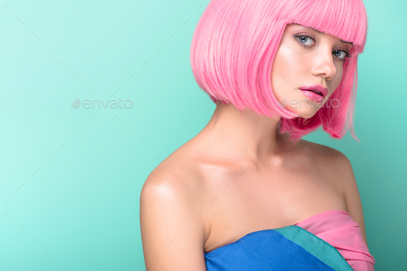 attractive young woman with pink bob cut looking at camera isolated on turquoise