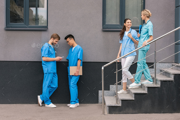 multicultural male medical students looking at smartphone near medical university
