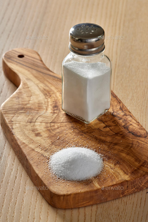 Spilled salt and a salt shaker on a cutting board