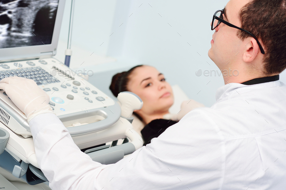 the doctor performs an ultrasound examination of the thyroid gland