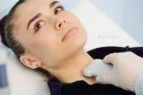 doctor in a modern diagnostic clinic examines the thyroid gland of a patient of a young attractive