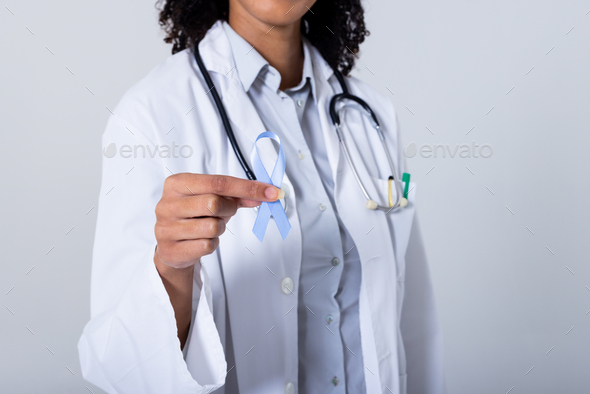 Midsection of african american mid adult female doctor holding blue stomach cancer awareness ribbon
