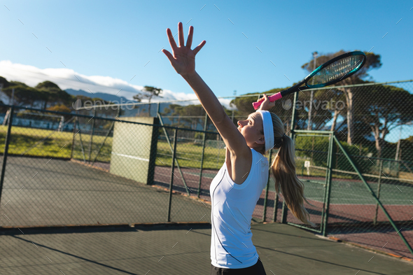 Side view of young female caucasian player serving at tennis court on sunny day