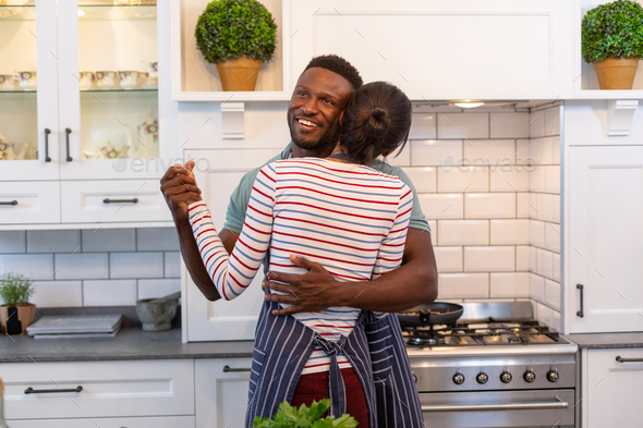 Multiracial romantic young couple dancing together in kitchen at home Stock Photo by Wavebreakmedia