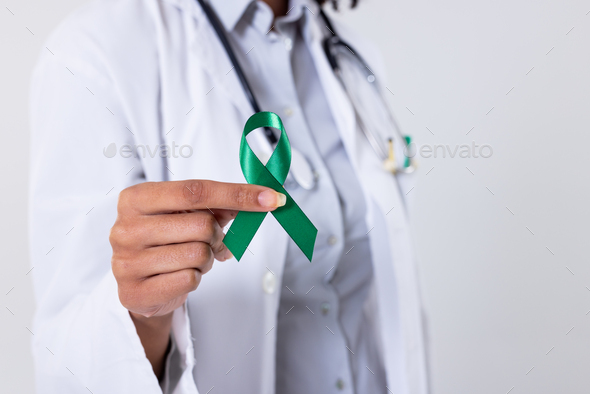 Midsection of african american mid adult female doctor holding green mental  health awareness ribbon Stock Photo by Wavebreakmedia