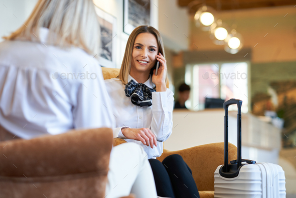 Two businesswomen with luggage in modern hotel lobby
