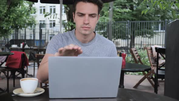 Man Leaving Cafe Terrace After Working on Laptop alt