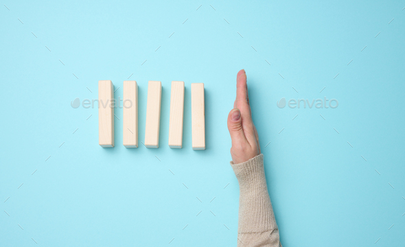 Hand stops the fall of wooden blocks on a blue background