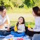 Happy family picnic. Asian parents, little girl drinking orange juice together during picnic - PhotoDune Item for Sale
