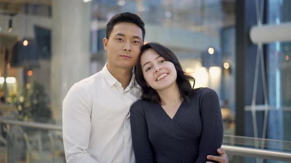 Portrait of Multiethnic Couple Hugging on Background of Shopping Center