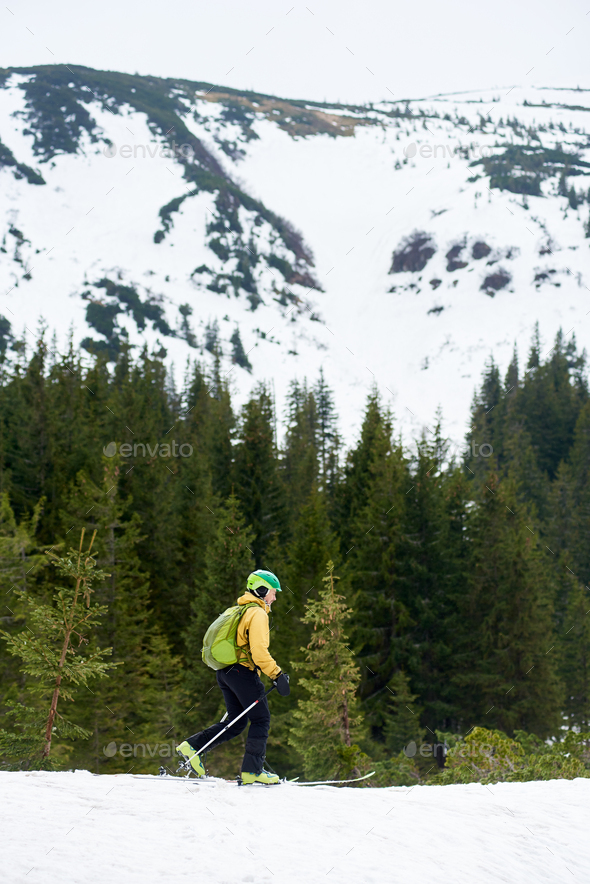 Side view of male walking alone on ski at foot of mountain