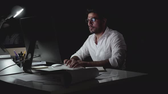 Dedicated Asian businessman seriously working on computer late at night in the office