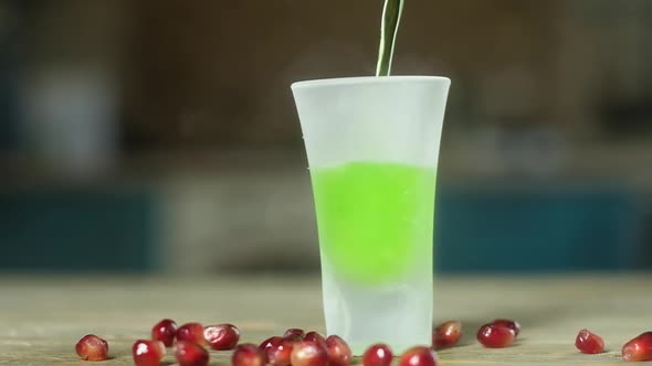 in the ice glass standing on the table poured green alcoholic beverage. alt