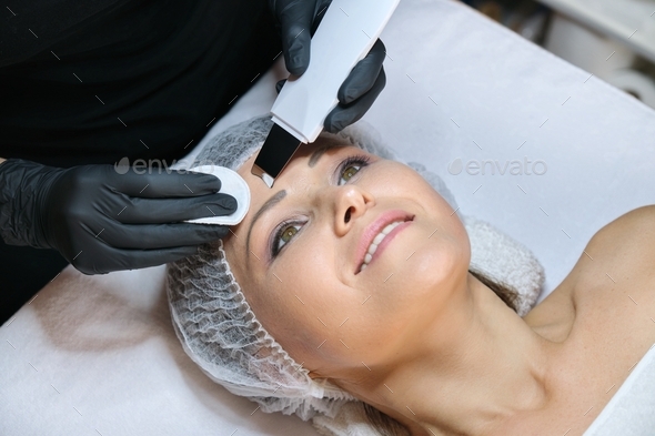 Cosmetology, mature woman receiving face cleaning with an ultrasonic device