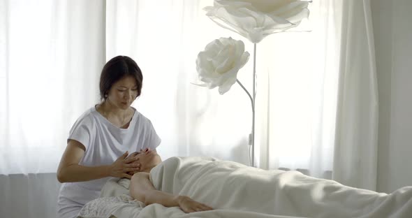 Cosmetologist Is Massaging Face of Adult Female Client of Beauty Salon alt