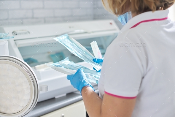 Female nurse doing sterilization of dental medical instruments in autoclave