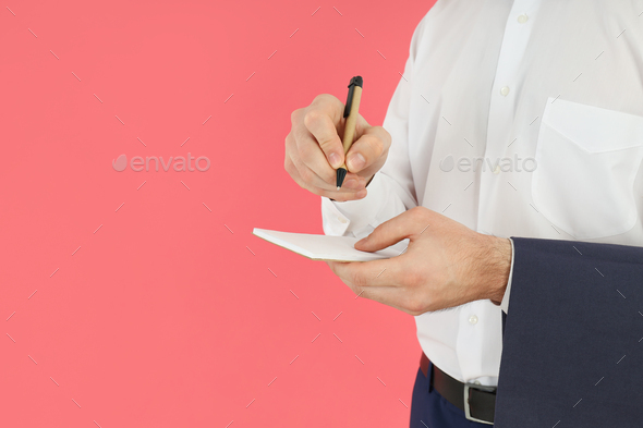 Male waiter writes order on pink background