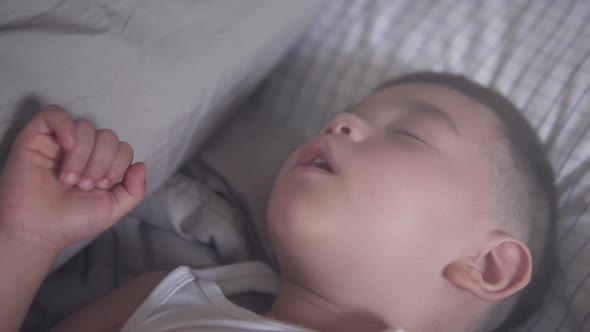 Slow motion close up and pull out shot of a little two years old Asian boy wearing summer clothes ha alt