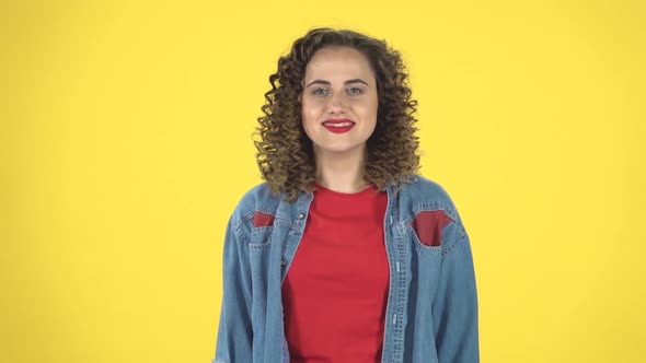 Smiling Girl Makes Sign Ok Over Yellow Background, Slow Motion alt
