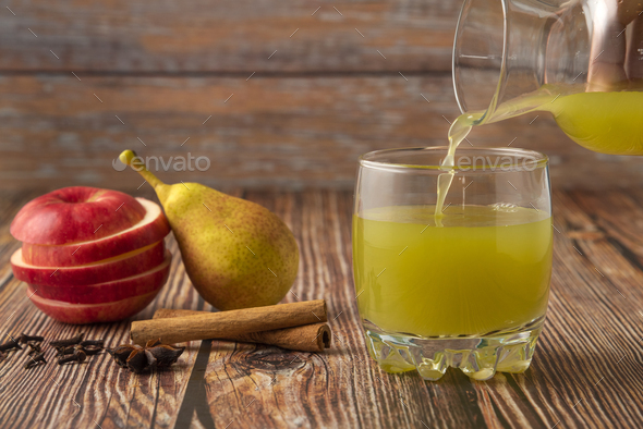 Pouring juice into glass on wooden background