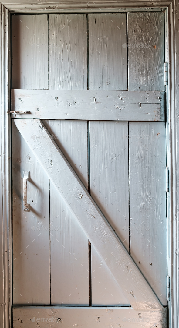Closed wooden painted door with a latch and a handle, entrance to the toilet, indoors