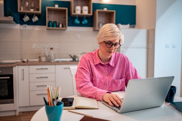 Woman working on a laptop in the kitchen at home