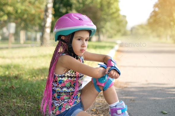 Serious thoughtful child in sports protective helmet and knee pads