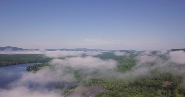 Flying Over White Puffy Low Clouds Over Wooded Lake Wassookeag in Maine alt