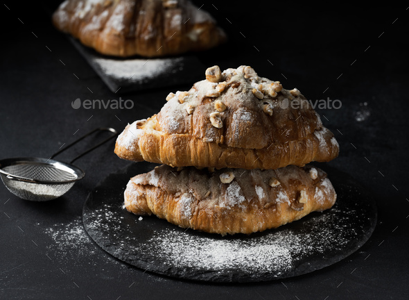 Baked croissant on a wooden board and sprinkled with powdered sugar