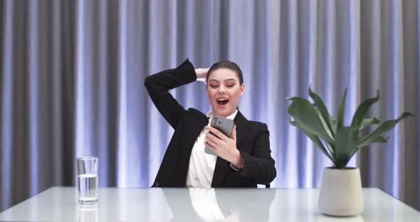 Businesswoman Sitting at the Table and Playing Game on a Smartphone Female Wins the Game Emotions of alt