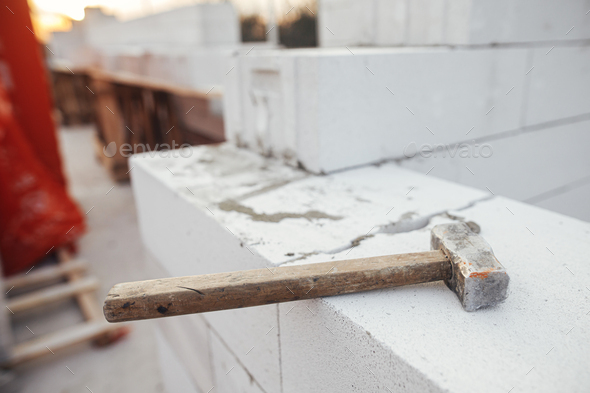 Hammer on autoclaved aerated concrete blocks. Laying white blocks close up. Masonry