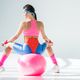 back view of athletic young woman sitting and exercising on fitness ball on grey - PhotoDune Item for Sale