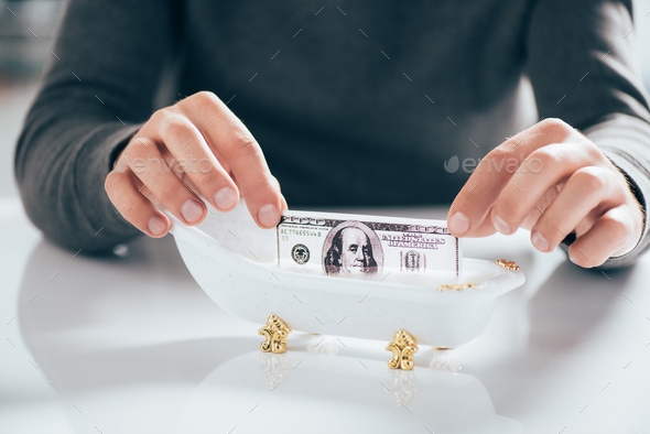 cropped shot of man washing dollar banknote in tub, money laundering concept - Stock Photo - Images