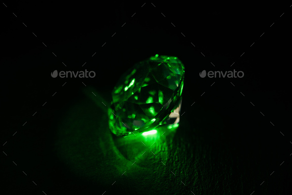 illuminated diamond with bright green neon light on dark background