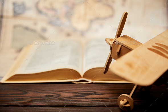 Selective focus of toy plane, book and map on wooden table