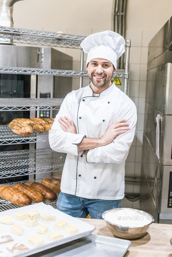 smiling male baker standing with arms crossed at kitchen Stock Photo by ...