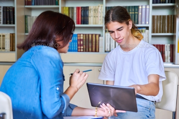 Woman school psychologist talking and helping student, teenage guy