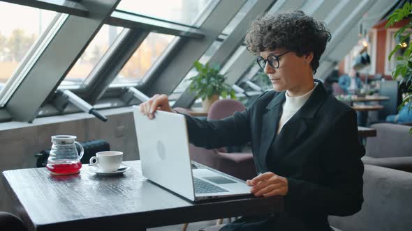 Attractive Young Woman in Suit Using Smartphone Then Working with Laptop in Cafe alt