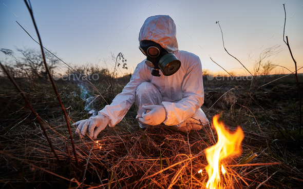 Unrecognizable person burning old dried grass in field